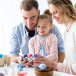 Cheerful family holding Easter painted eggs